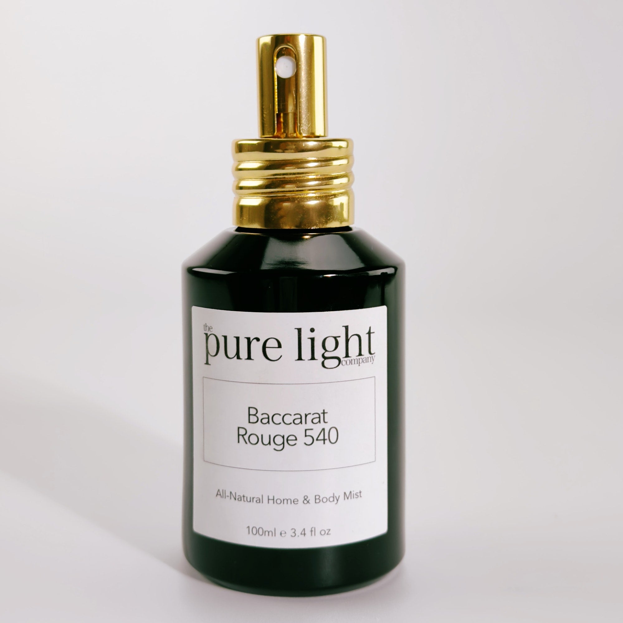 A glossy black spray mist bottle with a gold nozzle labeled 'Baccarat 540' by 'The Pure Light Company' on a white background