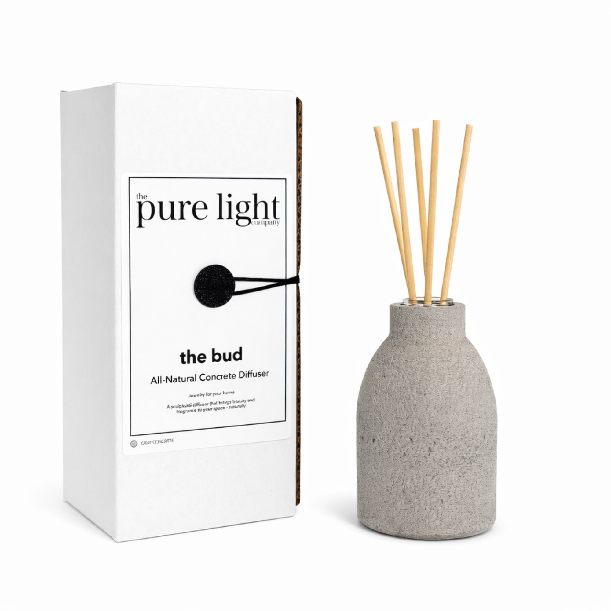 Gray concrete diffuser with wooden reeds next to its packaging on a white background