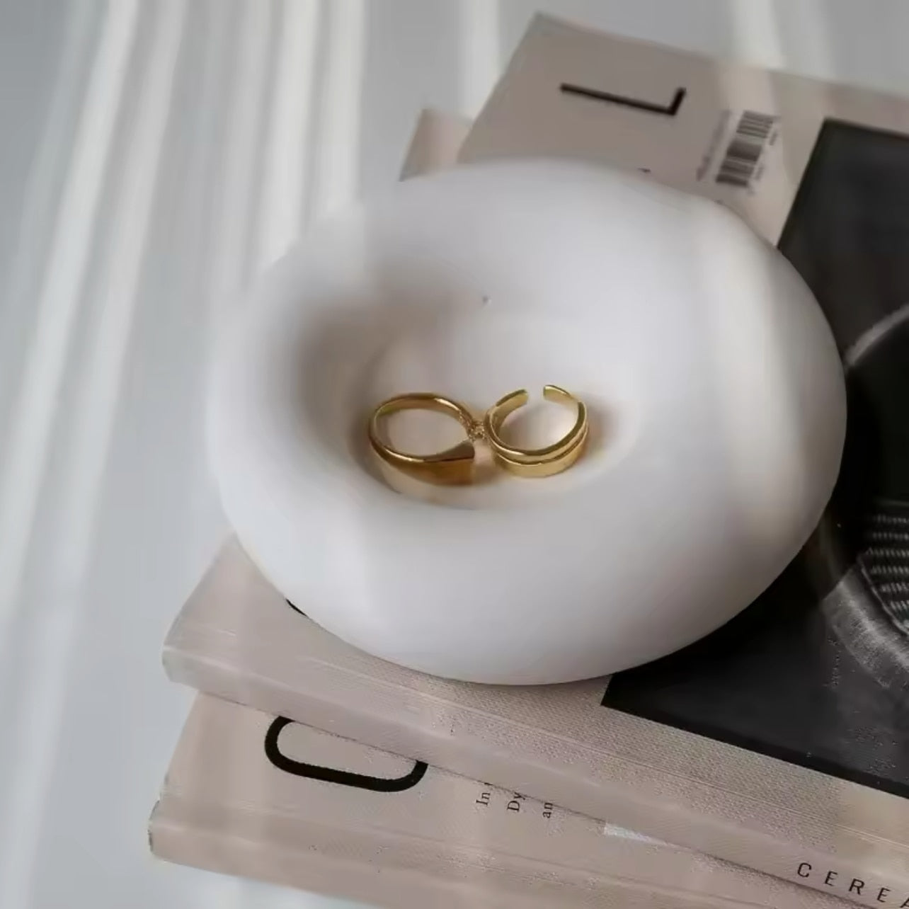 Gold ring on a white concrete trinket dish with 'the pure light company' branding.