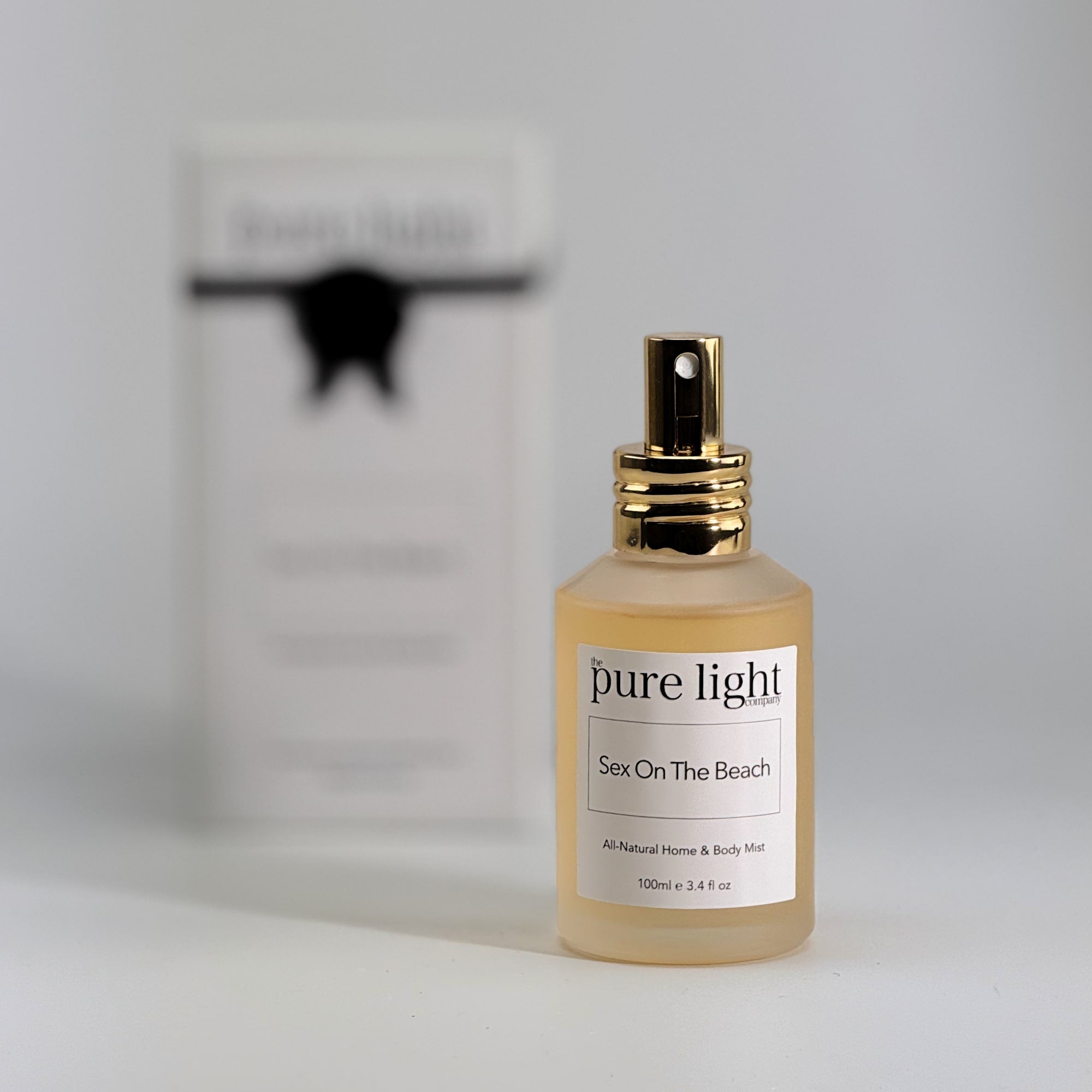 Bottle of The Pure Light Company "Sex On The Beach" All-Natural Home and Body Mist 100ml frosted glass bottle with a gold cap on a white background