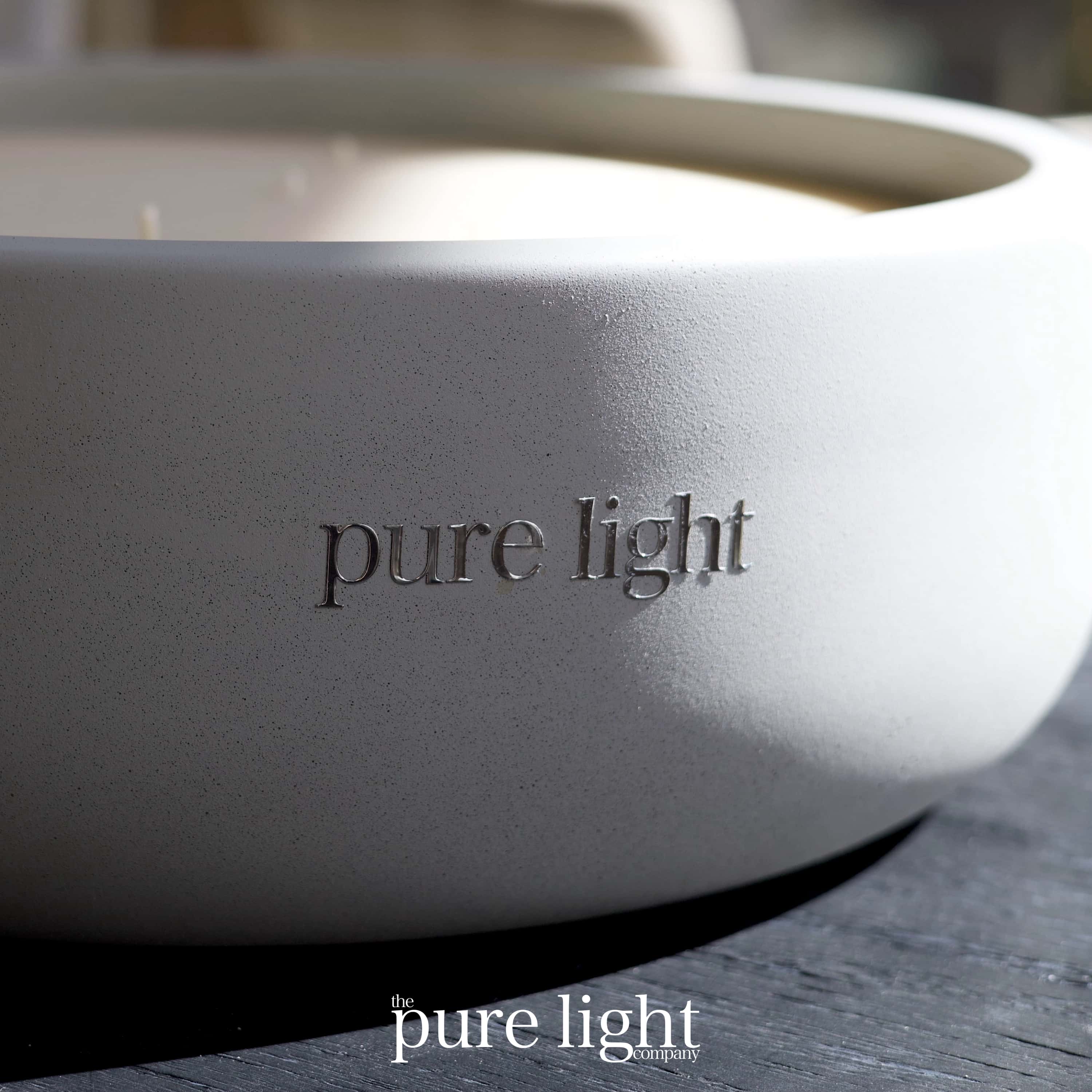 A huge, round Shampure Aveda Dupe concrete candle with 19 wicks on a dark table, with The Putre Light Company logo in silver.