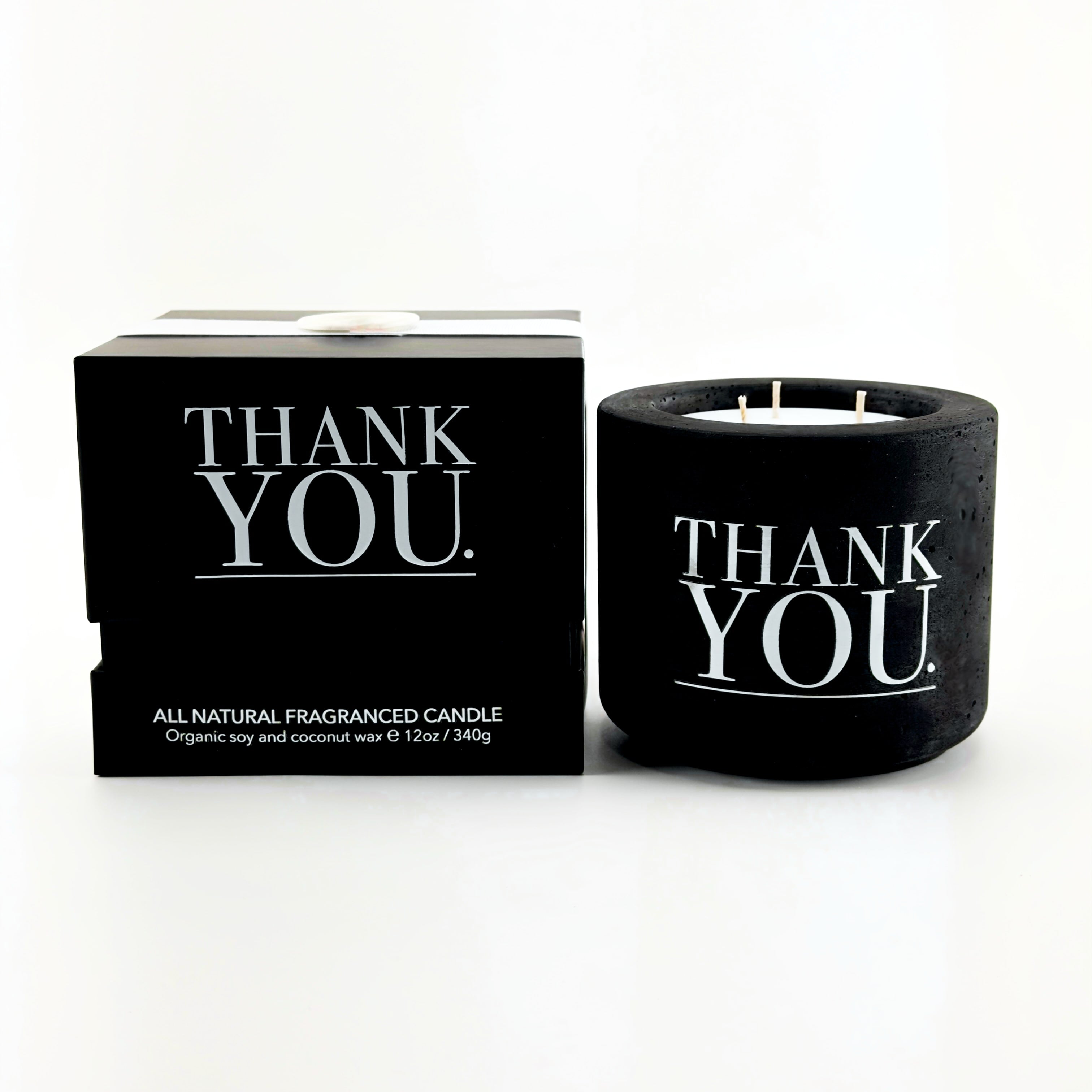 Black candle with 'THANK YOU' text and packaging on a white background by The Pure Light Company.