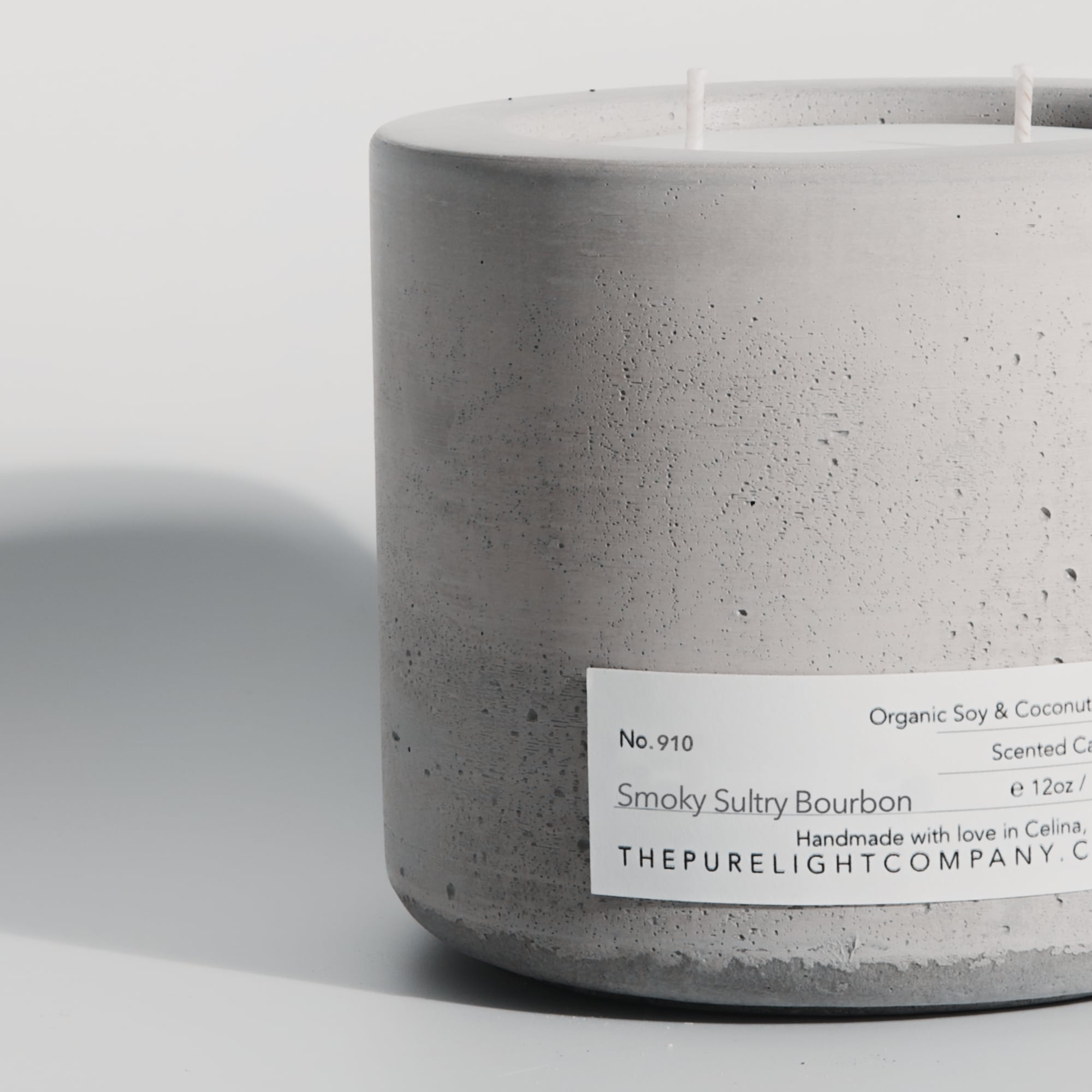 Close-up of the Large Smoky Sultry Bourbon gray concrete candle in a lifestyle setting with soft shadow, by The Pure Light Company