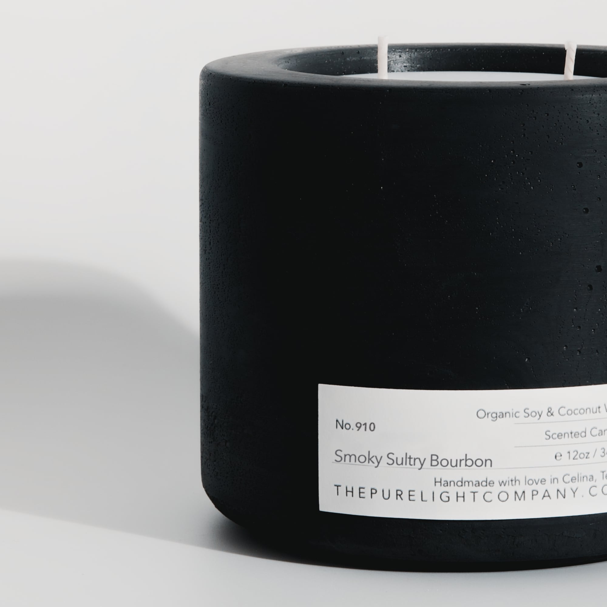 Close-up of the Large Smoky Sultry Bourbon black concrete candle in a lifestyle setting with soft shadow, by The Pure Light Company