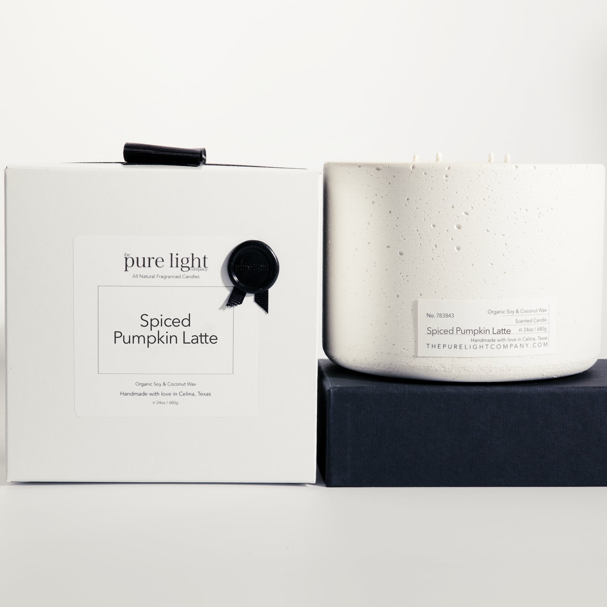 Extra large Spiced Pumpkin Latte black concrete candle on a prop beside a gift box with ribbon and wax seal by The Pure Light Company.