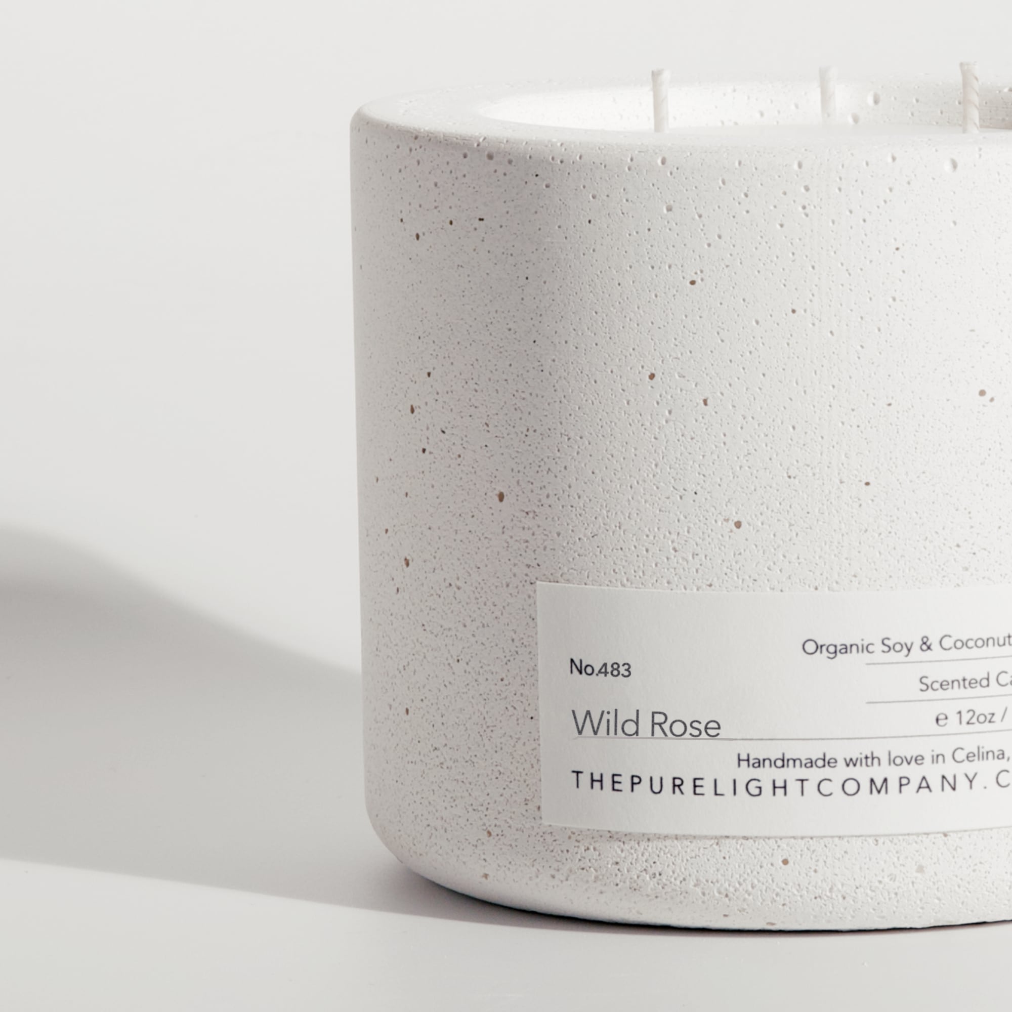 Close-up of the Large WILD ROSE white concrete candle in a lifestyle setting with soft shadow, by The Pure Light Company