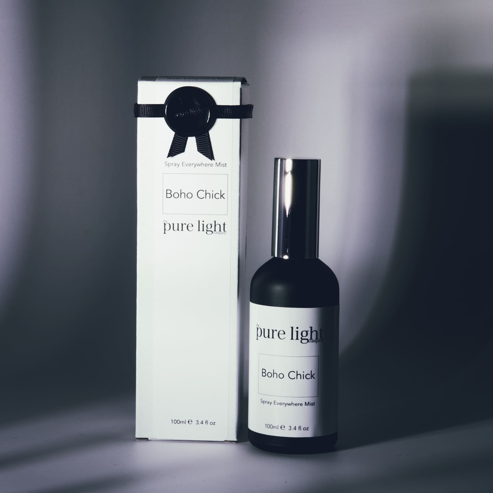 A product image featuring a black bottle of 'BOHO CHICK' fragrance with a white label and a spray pump, alongside its packaging box with a bow decoration.