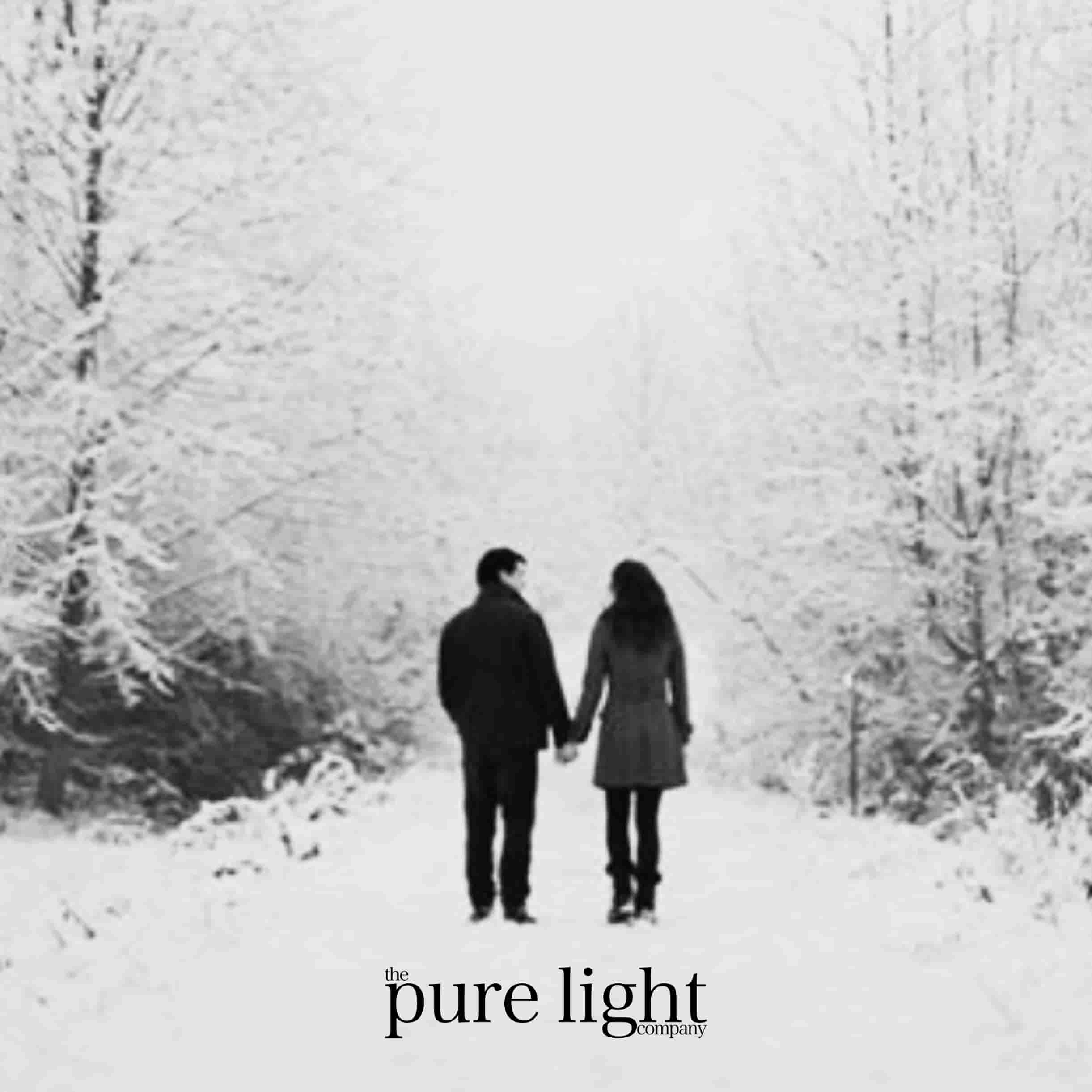 A couple walking holding hands surrounded by snow-covered trees for The Pure Light Company's Baby It's Cold Outside all-natural home fragrance collection