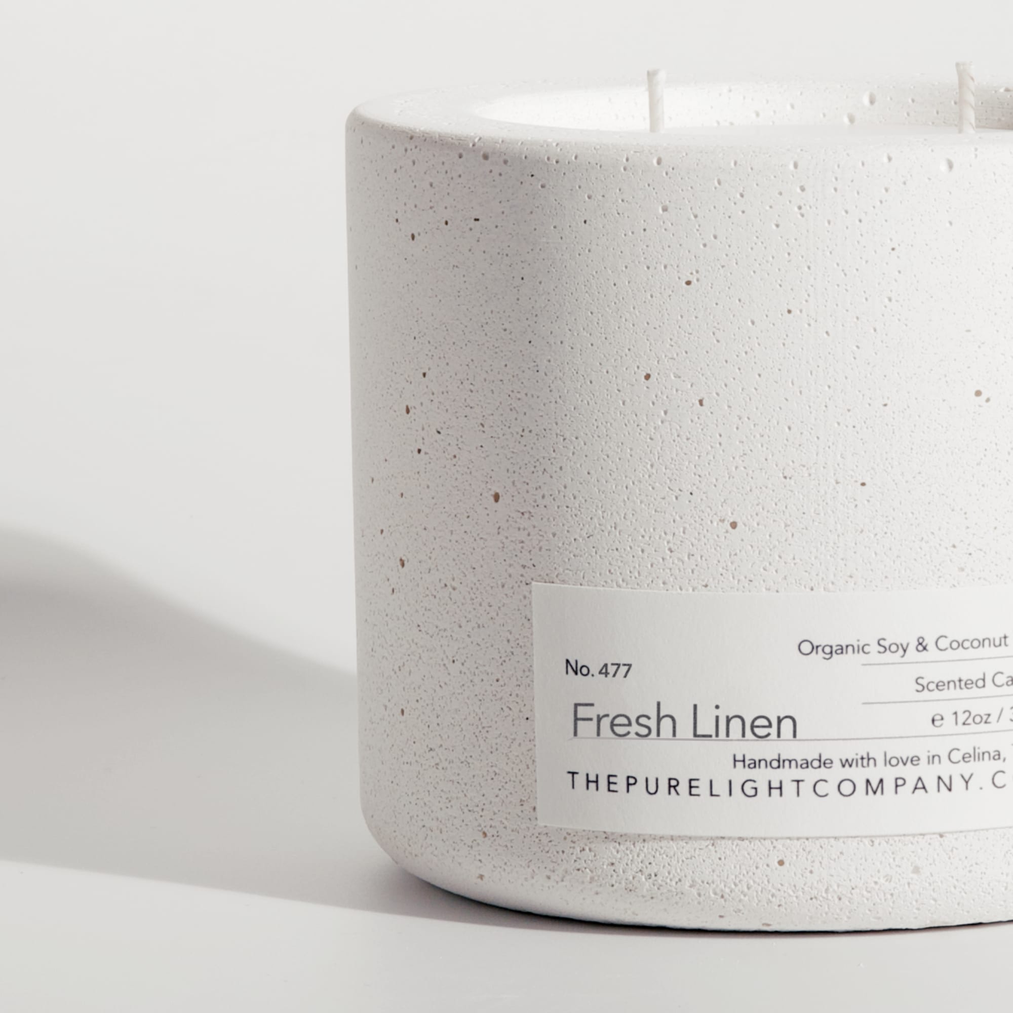 Close-up of the Large Fresh Linen white concrete candle in a lifestyle setting with soft shadow, by The Pure Light Company