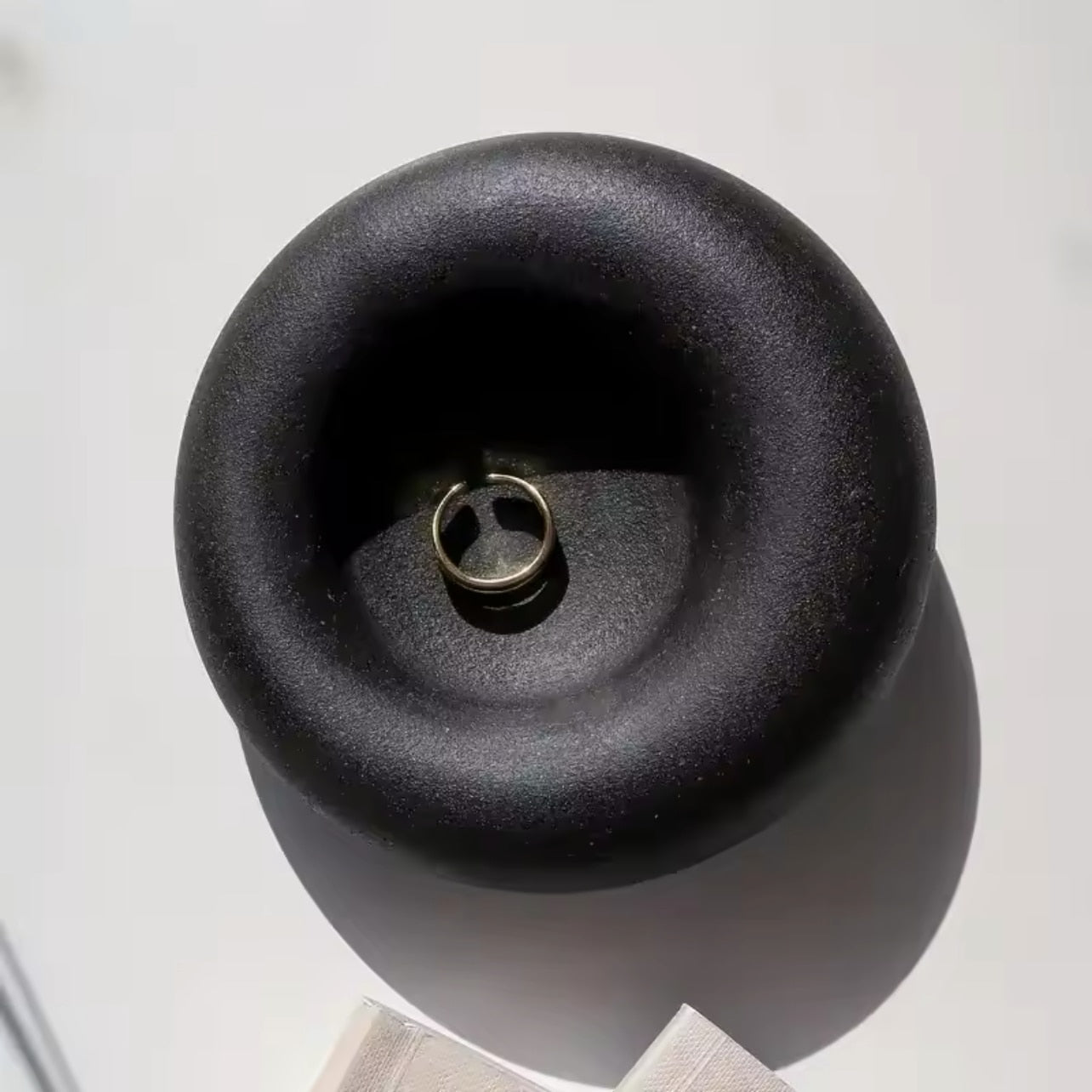 Black concrete trinket dish with 'the pure light company' text on a white background