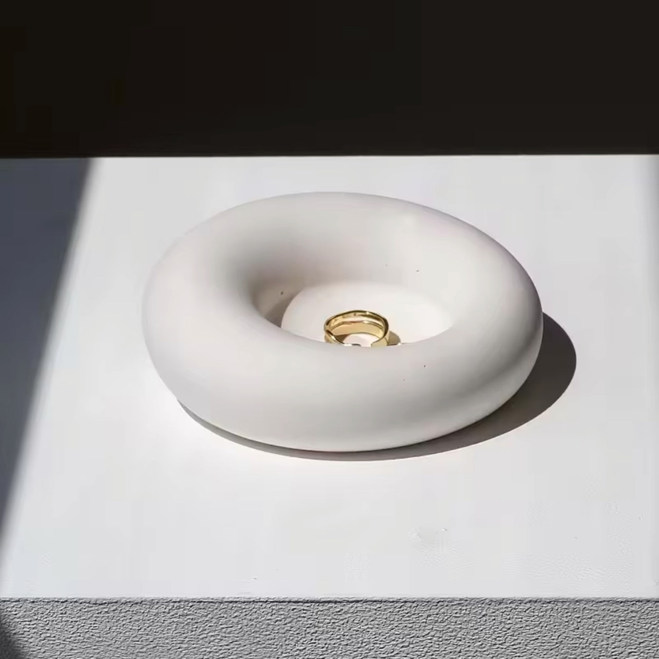 White concrete trinket dish on a white background with 'the pure light company' text.