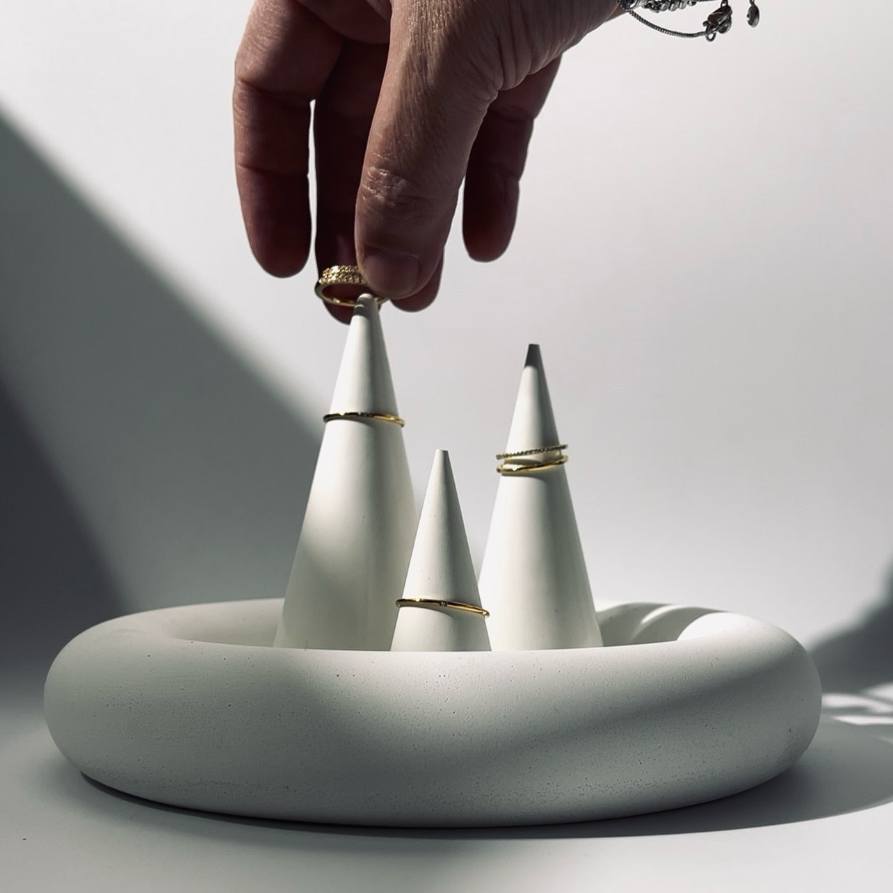 Hand placing a white cone with gold accents into a circular base, with 'the pure light company' branding.