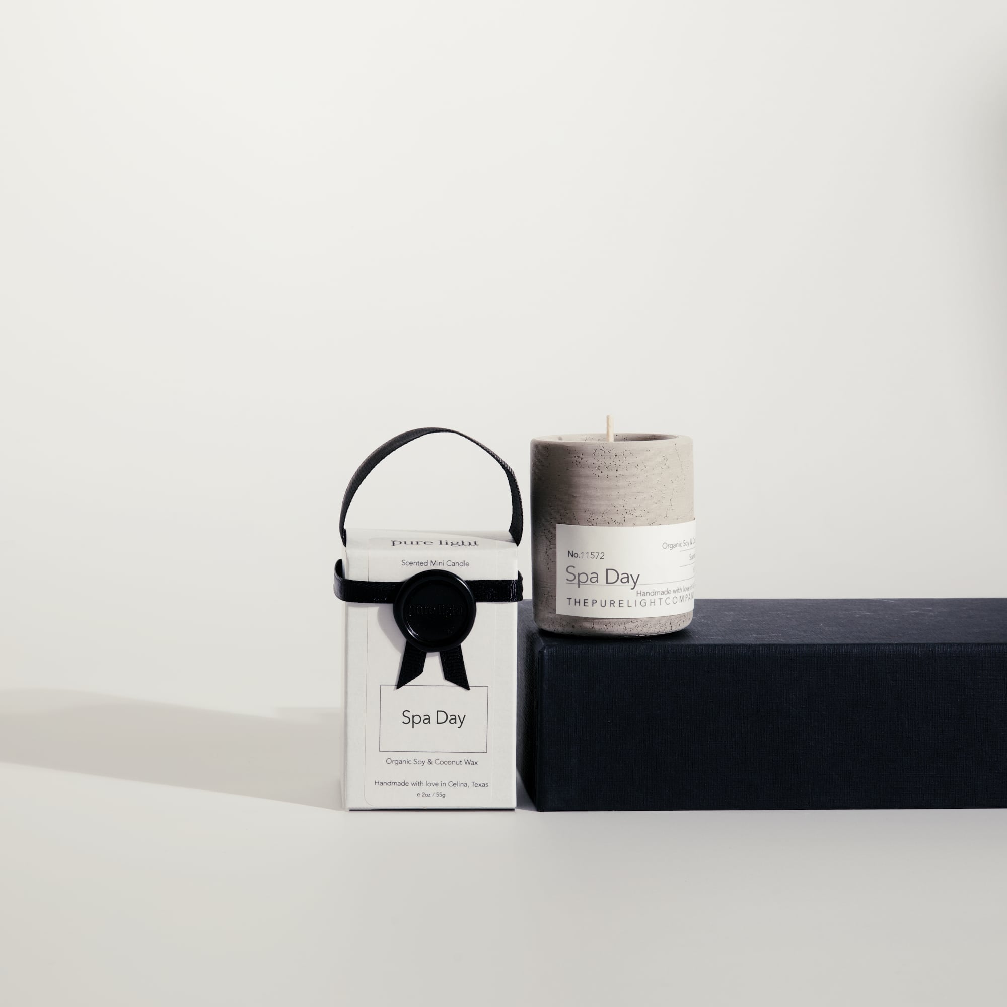 Mini Spa Day concrete candle on a prop beside a gift box with ribbon and wax seal by The Pure Light Company.
